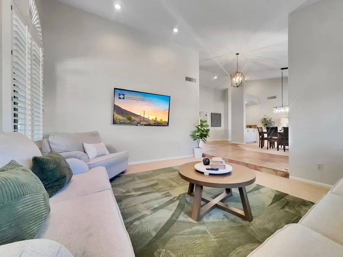A cozy interior scene with comfortable seating grouped around a coffee table, a large TV displaying a scenic image, and a decorative plant adding a touch of home. The space is bright and welcoming, ideal for movie nights or relaxed gatherings with family and friends.