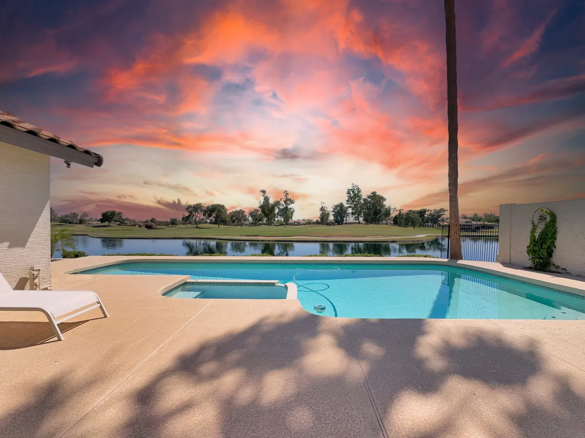 A sparkling swimming pool is set against a sunset sky, with a green lawn and tall palm trees creating a lush, resort-like atmosphere. The pool area is inviting, perfect for swimming, relaxing, or hosting poolside gatherings at different times of day.